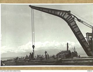 LAE, NEW GUINEA, 1943-10-13. LARGE FLOATING CRANE OF THE UNITED STATES SMALL SHIPS SECTION, RAISING A SUNKEN JAPANESE BARGE FROM THE DOCK AREA