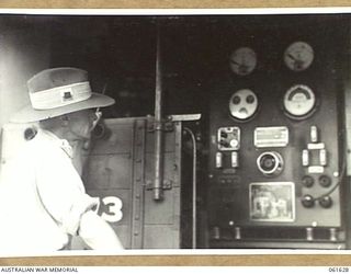 PORT MORESBY, NEW GUINEA. 1943-12-17. MAJOR GRAHAM OF THE CHIEF ENGINEER SIGNALS BRANCH, HEADQUARTERS, NEW GUINEA FORCE CHECKING A 25 KVA. 240 VOLT, SINGLE PHASE, ELECTRICITY GENERATING PLANT, ..
