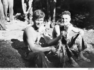 NX4545 Lieutentant James Copeman MC MM (left), pours water from his boot, and NX126259 Private Kenneth Bede Thomas Colbert lathers for a shave. The men, 2/3 Infantry Battalion members, have ..