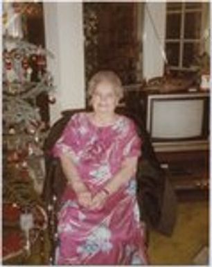 Older woman in pint floral muu-muu in front of Christmas tree