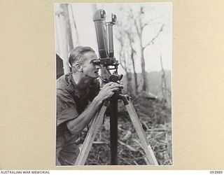 MOUNT SHIBURANGU, WEWAK, NEW GUINEA, 1945-07-12. LIEUTENANT-COLONEL W.S. HOWDEN, COMMANDING OFFICER 2/8 INFANTRY BATTALION, ADJUSTING THE STEREOSCOPIC TELESCOPE TO CHECK FEATURES ON "THE BLOT". AN ..