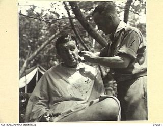 KILIGIA, NEW GUINEA. 1944-04-15. VX77933 PRIVATE W. BARNETT (1), A BARBER AT HEADQUARTERS 5TH DIVISION, GIVING A HAIRCUT TO NX37475 LIEUTENANT R. DAWE, OFFICER COMMANDING 3RD ARMOURED DIVISION ..