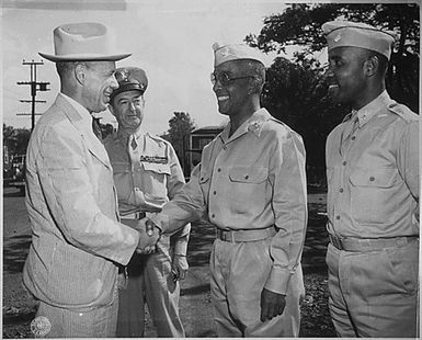 "After inspecting a regiment of Negro artillerymen during a visit to Hawaii, Under Secretary of War Robert P. Patterson congratulates Col. Chauncey M. Hooper,...commander of the unit, while Lt. Gen. Robert C. Richardson, Jr. and Col. Harry B. Reubel,...watch with approval."