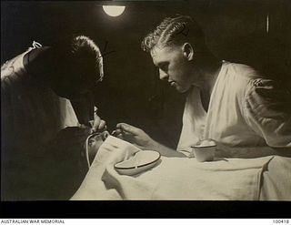 Port Moresby, New Guinea. 1944-05-13. Lieutenant P. B. Stevens (left), Ophthalmic Section, 128th Australian General Hospital, removing a steel filing from a patient's eye, assisted by Private R. E. ..