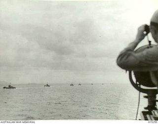 1943-07-12. AMERICANS ADVANCE INTO TROBRIAND ISLANDS. THROUGH BINOCULARS AN AMERICAN OFFICER WATCHES THE PROGRESS OF THE CONVOY. (NEGATIVE BY N. BROWN)
