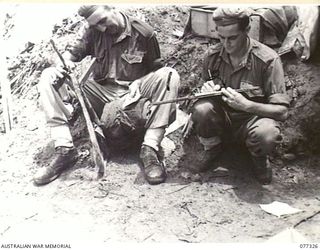 TOROKINA AREA, BOUGAINVILLE ISLAND. 1944-11-29. NX116813 CAPTAIN A.J.F. GAUL, OFFICER- IN- CHARGE, D COMPANY, 9TH INFANTRY BATTALION (1) DICTATING A REPORT TO QX56448 PRIVATE C. ESDALE (2) ON THE ..