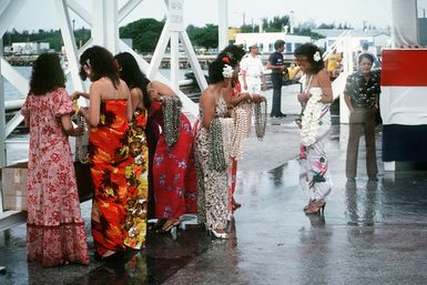 Guamanian women wait at Naval Station Guam to welcome the crew of the combat stores ship USS NIAGARA FALLS (AFS 3) into port