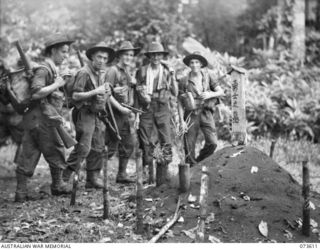 GAMAN, NEW GUINEA. 1944-05-27. TROOPS OF THE 35TH INFANTRY BATTALION PAUSE ALONGSIDE A JAPANESE GRAVE ON THE MARUKINAM TRACK DURING THEIR ADVANCE TO WEWAK. IDENTIFIED PERSONNEL ARE:- V151654 ..