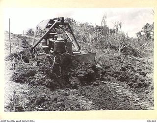 YAMIL 3, NEW GUINEA, 1945-07-23. A BULLDOZER OF 10 PLATOON, 2/14 FIELD COMPANY, ROYAL AUSTRALIAN ENGINEERS, MAKES QUICK WORK OF LEVELLING OFF THE ROUGH SURFACE OF THE YAMIL-MAPRIK ROAD