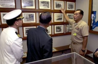 US Navy MASTER CHIEF PETTY Officer Felise Tupola (Right) shows historic photographs of the 1941 attack on Pearl Harbor to General Cho, Yung Kil (Center), Chairman, Joint Chiefs of STAFF, Republic of Korea, and his interpreter, Commander Sohn, Do Ik, at the Commander In CHIEF, Pacific Fleet, boathouse museum on Pearl Harbor on October 30th, 2000. The General toured the museum and then took a barge cruise to the USS Arizona Memorial for a wreath laying ceremony (Not shown). GEN Cho is in Hawaii this week attending the Chiefs of Defense Conference