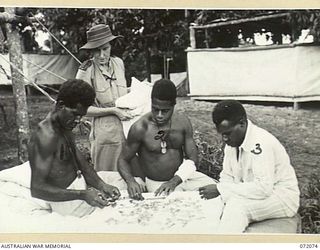 HELDSBACH PLANTATION, NEW GUINEA. 1944-04-06. THREE DECORATED MEMBERS OF THE PAPUAN INFANTRY BATTALION PLACE TOGETHER A JIG-SAW PUZZLE OUTSIDE THEIR WARD AT THE 106TH CASUALTY CLEARING STATION ..