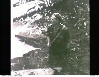 THE SOLOMON ISLANDS, 1945-05-02. AN AUSTRALIAN SOLDIER KNEE DEEP IN MUD ON PATROL ON BOUGAINVILLE ISLAND. (RNZAF OFFICIAL PHOTOGRAPH.)