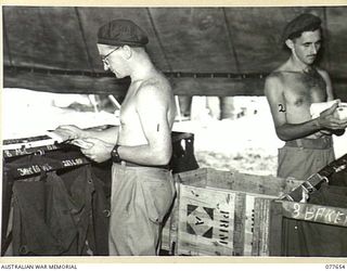 JACQUINOT BAY, NEW BRITAIN. 1944-12-19. NX152373 CORPORAL C.F. MCALISTER (1) AND WX16695 SERGEANT R. HEDLEY (2), 7TH BASE POSTAL UNIT, SORTING CHRISTMAS MAIL FOR DELIVERY TO UNITS IN THE AREA