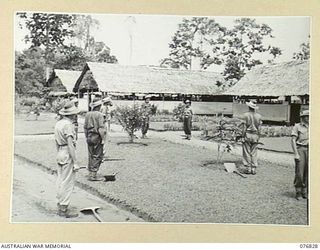 LAE, NEW GUINEA. 1944-11-11. PATIENTS WORKING IN THE GARDENS OF THE 112TH CONVALESCENT DEPOT, DOWN TOOLS AND STAND SILENTLY TO ATTENTION FOR THE TWO MINUTES SILENCE AT 11AM, ON ARMISTICE DAY
