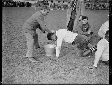 A Fijian player receiving assistance during a rugby game with the New Zealand Maori team