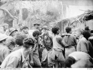 Australian troops and native carriers stop at an allied base at Eora Creek Village on their way out of a forward area in the Kokoda region for a well-earned spell. The soldier front left is ..
