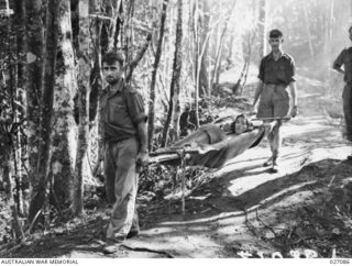 PAPUA, NEW GUINEA. 1942-10. A JAPANESE PRISONER BEING BROUGHT IN ON A ROUGH STRETCHER BY TWO AUSTRALIANS IN THE HILLY COUNTRY NEAR EORIBAIWA. HE WAS VERY WEAK AND COULD NOT STAND