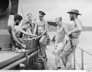 BAIEN AREA, NEW BRITAIN. 1945-01-26. GUNNERS ABOARD THE ML802 OF THE ROYAL AUSTRALILAN NAVY PORT DIRECTORATE, JACQUINOT BAY, LOADING .5" AMMUNITION INTO BROWNING GUN BELTS IN PREPARATION FOR THEIR ..