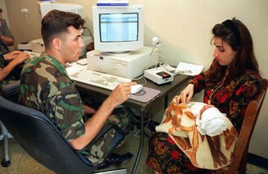 Army SPECIALIST Brandon Files from the 502nd Military Intelligence Company, Fort Polk, Louisiana, creates identification cards for Kurdish evacuees at Andersen Air Force Base, Guam, as part of Operation PACIFIC HAVEN. The operation, a joint humanitarian effort conducted by the US military, entails the evacuation of over 2,100 Kurds from northern Iraq to avoid retaliation from Iraq for working with the US government and international humanitarian agencies. The Kurds will be housed at Andersen AFB, while they go through the immigration process for residence in the United States