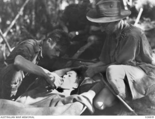 PAPUA, NEW GUINEA. 1942-10. WOUNDED JAPANESE PRISONER BEING CARED FOR BY AUSTRALIAN STRETCHER BEARERS