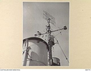 MIOS WUNDI, DUTCH NEW GUINEA. 1944-11-15. A RADAR GRID ON THE MAST OF HMAS STAWELL WITH RATINGS ALONGSIDE THE INSULATORS