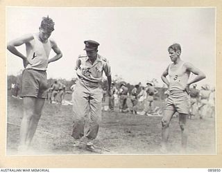 HERBERTON, QLD. 1945-01-19. GUNNER BAIN, 2/12 FIELD REGIMENT, (1), AND SERGEANT MCHENRY, 2/23 INFANTRY BATTALION, (3), TOSS TO DECIDE WHO TAKES THE SASH FOR THE 880 YARDS SPRINT IN WHICH THEY DEAD ..