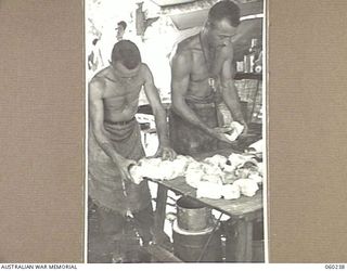 DUMPU, NEW GUINEA. 1943-11-05. SX4515 LANCE CORPORAL W. FERRIS (LEFT) AND SX4745 SERGEANT E. S. LOWE (RIGHT) COOKS OF THE 2/6TH AUSTRALIAN FIELD AMBULANCE SEPARATING ROLLS AFTER COOLING