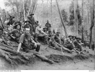 PAPUA, NEW GUINEA. 1942-10. A PARTY OF MEN OF THE 2/1ST AUSTRALIAN PIONEER BATTALION REST ON THE JUNGLE SLOPES TO UBERI, WHERE THEY HAVE BEEN WORKING HARD MAKING A TRACK TO GET TROOPS FORWARD