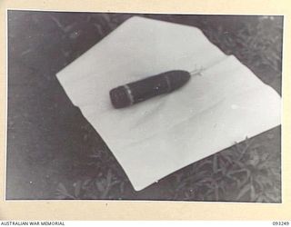 CHABAI/SORAKEN AREA, BOUGAINVILLE, 1945-06-20. A CAPTURED IMPROVISED MINE, WHICH CAN BE ELECTRICALLY DETONATED, MADE FROM A JAPANESE 75 MM SHELL. IT IS PHOTOGRAPHED OUTSIDE 11 INFANTRY BRIGADE ..