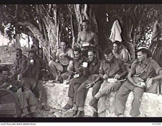 NAURU ISLAND. 1945-09-14. TROOPS OF THE 31/51ST INFANTRY BATTALION ENJOYING THEIR LUNCH UNDER A LARGE TREE BEFORE THE COMMENCEMENT OF THE AUSTRALIAN FLAG RAISING CEREMONY