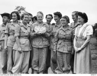 LAE AREA, NEW GUINEA. 1945-08-19. GRACIE FIELDS, WITH MEMBERS OF THE SISTERS' MESS, AUSTRALIAN ARMY WOMEN'S MEDICAL SERVICE, 2/8 GENERAL HOSPITAL, HOLDING A CAKE PRESENTED TO HER BY THE CANTEEN ..