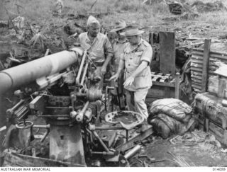 1943-01-14. A THREE INCH ANTI-AIRCRAFT GUN CAPTURED FROM THE JAPANESE AT THE GOVERNMENT GARDENS, BUNA. IT IS BEING INSPECTED BY LIEUT. GENERAL EICHELBERGER AND GENERAL SIR THOMAS BLAMEY. THE MOUNDS ..