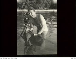 VIVIGANI, GOODENOUGH ISLAND, PAPUA. 1943-09-26. CLOTHING COUPONS DO NOT WORRY 71710 PILOT OFFICER O. C. SMITH OF WANGARATTA, VIC, WAIST-DEEP NAKED IN A JUNGLE SWAMP. HE IS A SURVEYOR WITH NO. 7 ..