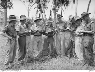 LAE, NEW GUINEA. 1944-11-02. NX110846 CAPTAIN P.R.OL. LAURENCE, STAFF CAPTAIN, 14/32ND INFANTRY BATTALION (1) COMPLETING THE UNIT EMBARKATION DETAILS WITH HIS OFFICERS. IDENTIFIED PERSONNEL ARE:- ..