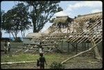 Men weaving roof of building