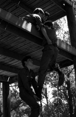 Airmen climb up a tower during obstacle training in a civil air patrol encampment