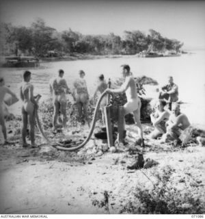 NEW GUINEA. 1944-03-10. VX10828 CAPTAIN J. SMITH (1), OFFICER COMMANDING THE 5TH DIVISION RECEPTION CAMP, WITH OFFICERS AND MEN OF THE CAMP WHO ARE HOSING EACH OTHER DOWN AFTER A BATHE IN THE BAY. ..