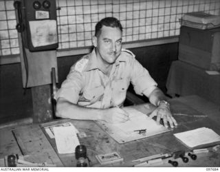 NADZAB, NEW GUINEA. 1945-10-05. CAPTAIN A.H. MACLEAN, ADMINISTERING COMMANDER M SPECIAL UNIT INTELLIGENCE BATTALION, NADZAB, IN HIS OFFICE AT THE ALLIED INTELLIGENCE BUREAU, NEW GUINEA HEADQUARTERS