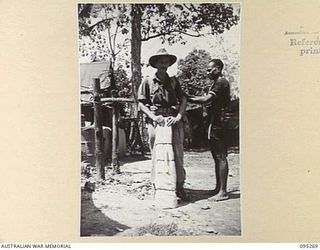 PALMALMAL, JACQUINOT BAY, NEW BRITAIN, 1945-08-13. A MEMBER OF THE ROYAL PAPUAN CONSTABULARY ASSISTS WARRANT OFFICER 1 H. BENNETT, HEADQUARTERS 5 DIVISION TO ADJUST HIS WEBBING EQUIPMENT BEFORE HIS ..