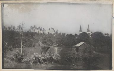 View in Papua New Guinea with two spires, one flying a red cross flag, 1914