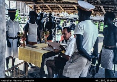 European official checking papers with Papua New Guineans waiting