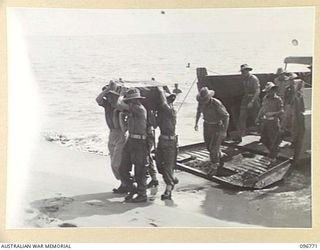 SORAKEN, BOUGAINVILLE, 1945-09-17. TROOPS CARRYING COFFIN ASHORE FROM BARGE FOR BURIAL OF REMAINS OF SAPPER R.C. KENNON, KILLED IN ACTION ON BOUGAINVILLE. MEMBERS OF 42 PORT LANDING CRAFT COMPANY ..