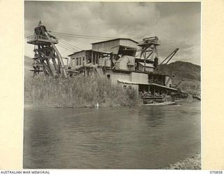 WAU - LAE ROAD, NEW GUINEA, 1944-02-20. AN ABANDONED GOLD MINING DREDGE ON THE BULOLO RIVER APPROXIMATELY A MILE SOUTH OF THE BULOLO - WATUT RIVER JUNCTION. ALTHOUGH GRASS GROWS IN THE DREDGE'S ..