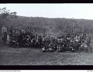 WAREO, NEW GUINEA. 1943-12-09. AS THE FLAG OF THE 2/23RD AUSTRALIAN INFANTRY BATTALION WAS BEING HOISTED, A SALVATION ARMY OFFICER WAS PUTTING UP HIS SIGN, AFTER HAVING FOLLOWED THE BATTALION RIGHT ..