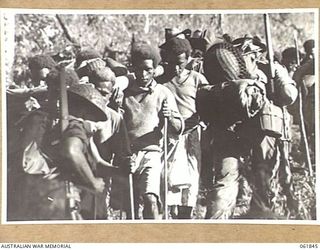 KOKODA TRAIL, NEW GUINEA. 1943-12-19. MEN OF THE 2/9TH AUSTRALIAN INFANTRY BATTALION AND NATIVE CARRIERS ACTING A EXTRAS DURING THE FILMING OF "RATS OF TOBRUK" BY CHAUVEL'S PRODUCTIONS