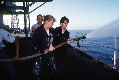 Machinist Mate Third Class (MM3) Michelle McCranie (left), who just recently transferred to the amphibious command ship USS BLUE RIDGE (LCC-191) receives some hands on experience in the use of a high pressure fire hose during damage control training on the main deck of the ship. She is being assisted by SEAMAN (SN) Stormi Frusetta. The ship is operating off the coast of Guam during exercise Tempo Brave '94