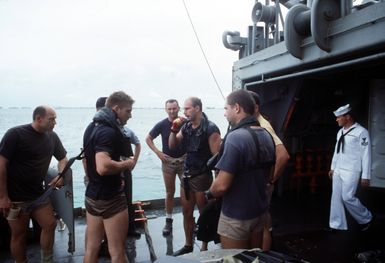 Divers confer aboard the salvage and rescue ship USS BRUNSWICK (ATS-3) as the ship conducts operations near Majuro Atoll. The BRUNSWICK will be in the islands for 90 days while its crew salvages a wreck that is blocking the harbor at the island of Jaluit