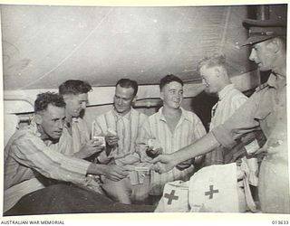 1942-11-23. LT. R.R. NIXON OF SYDNEY DISTRIBUTING CIGARETTES AND OTHER COMFORTS TO HOSPITAL PATIENTS IN NEW GUINEA ON BEHALF OF THE AUSTRALIAN RED CROSS. (NEGATIVE BY BOTTOMLEY)
