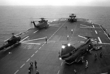 A view of helicopters on the deck of the amphibious assault ship USS SAIPAN (LHA-2).The helicopters are, starting at left: an AH-1 Sea Cobra, two H-53 Sea Stallion and an H-46 Sea Knight. The ship and helicopters are involved in a NATO exercise Display Determination '81