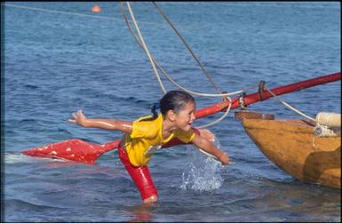 Child playing in water, with boat